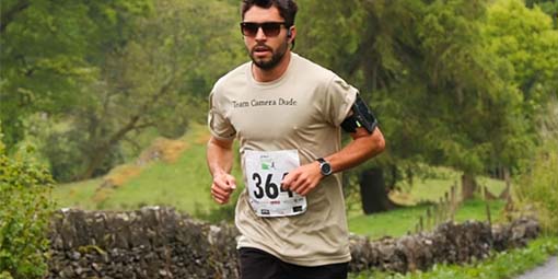 Hombre con dorsal corriendo con árboles al fondo